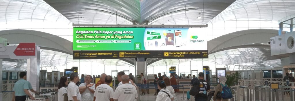 Pegadaian LED ad at Kualanamu Airport promoting “Safe Gold Installments” with suitcase and app visuals.