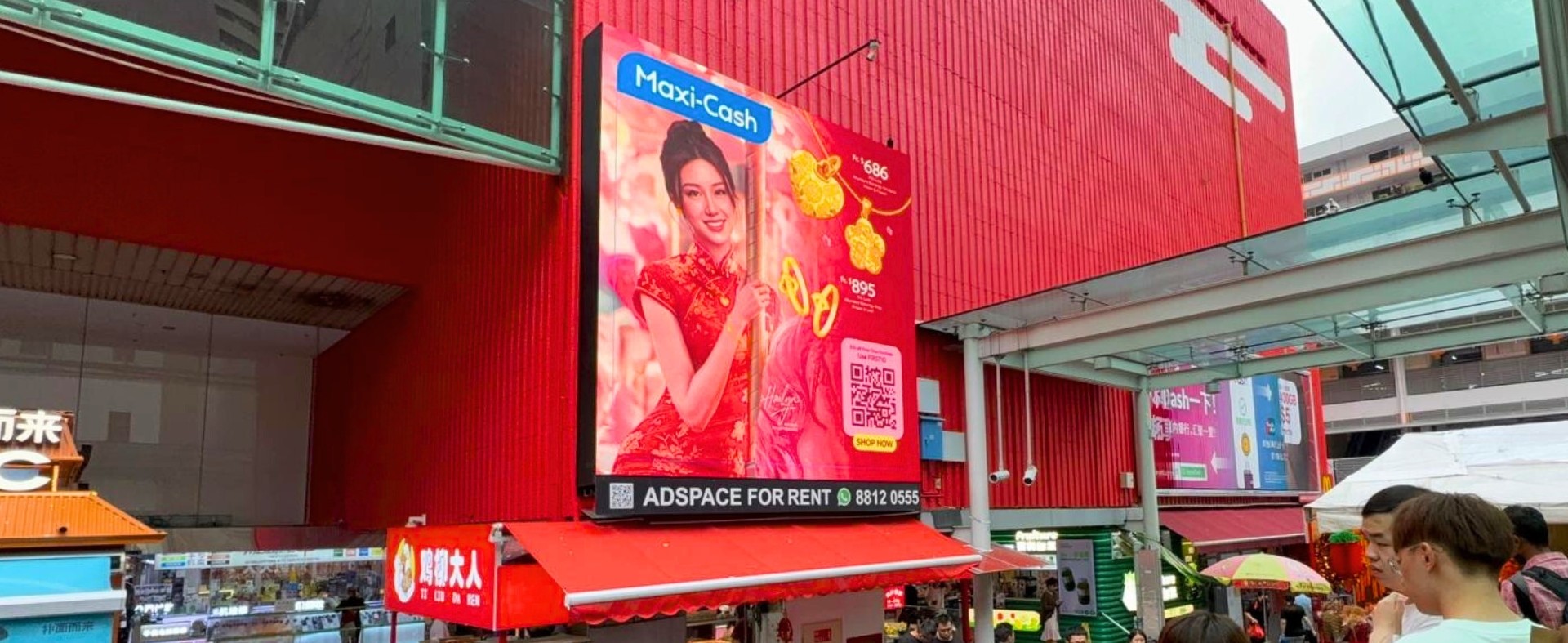 Maxi-Cash campaign displayed on a high-visibility DOOH LED screen at People’s Park Centre Singapore, premium outdoor advertising location with strong pedestrian traffic.